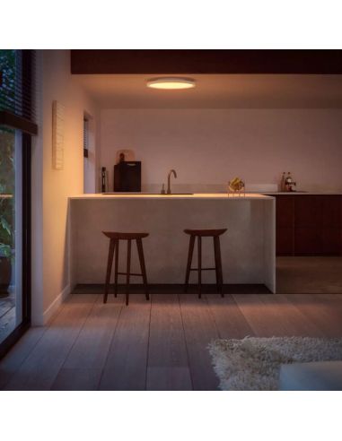 Panneau LED intelligent rond blanc Philips Hue Surimu WA dans un salon