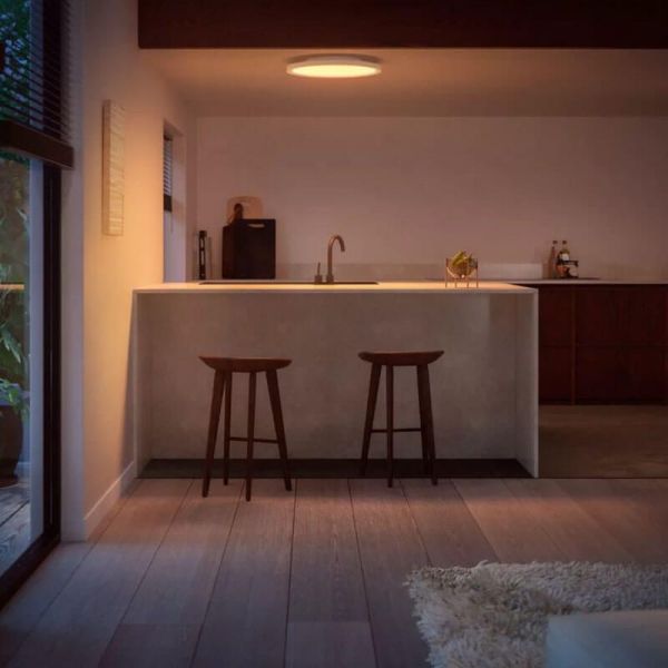 Panneau LED intelligent rond blanc Philips Hue Surimu WA dans un salon