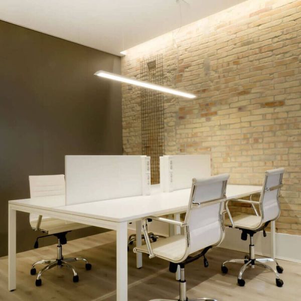 Arkoslight Slimgot Lâmpada de teto branca iluminada sobre um espaço de trabalho | LeonLeds.com