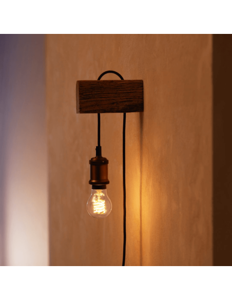 Bombilla inteligente Philips HueWhite 7W 2100K 550lm A60 E27 colocada en un aplique de pared