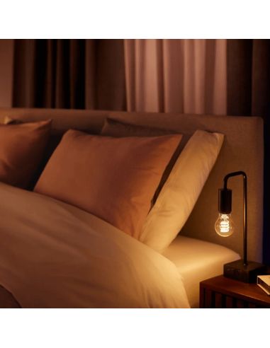 Lâmpada inteligente Philips Hue White Ambiance 7W 2200-4500K Fil 550lm A60 E27 em uma luminária de mesa