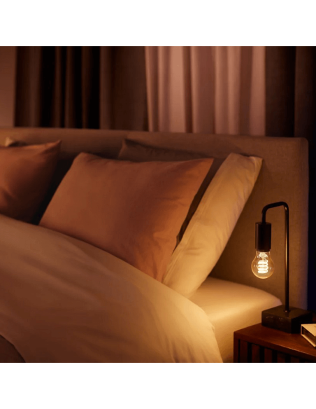 Bombilla inteligente Philips Hue White Ambiance 7W 2200-4500K Fil 550lm A60 E27 en una lámpara de mesa