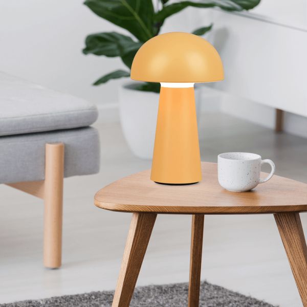 Lámpara de sobremesa Lennon amarillo encima de una mesa encendida| LeonLeds