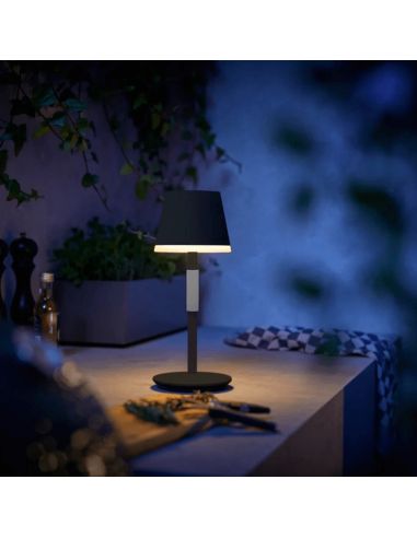 Lámpara de mesa portátil LED inteligente Hue Go negro-gris encendida en una mesa